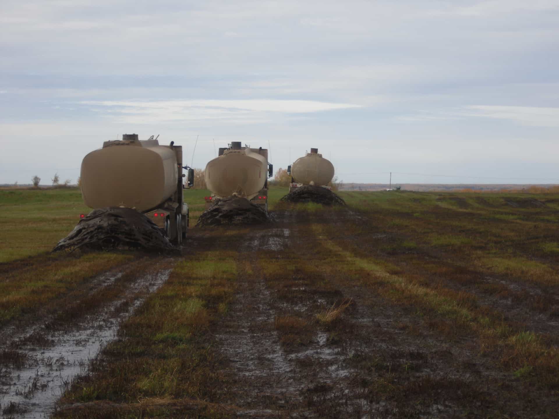 three lambourne trucks applying biosolids on farm land